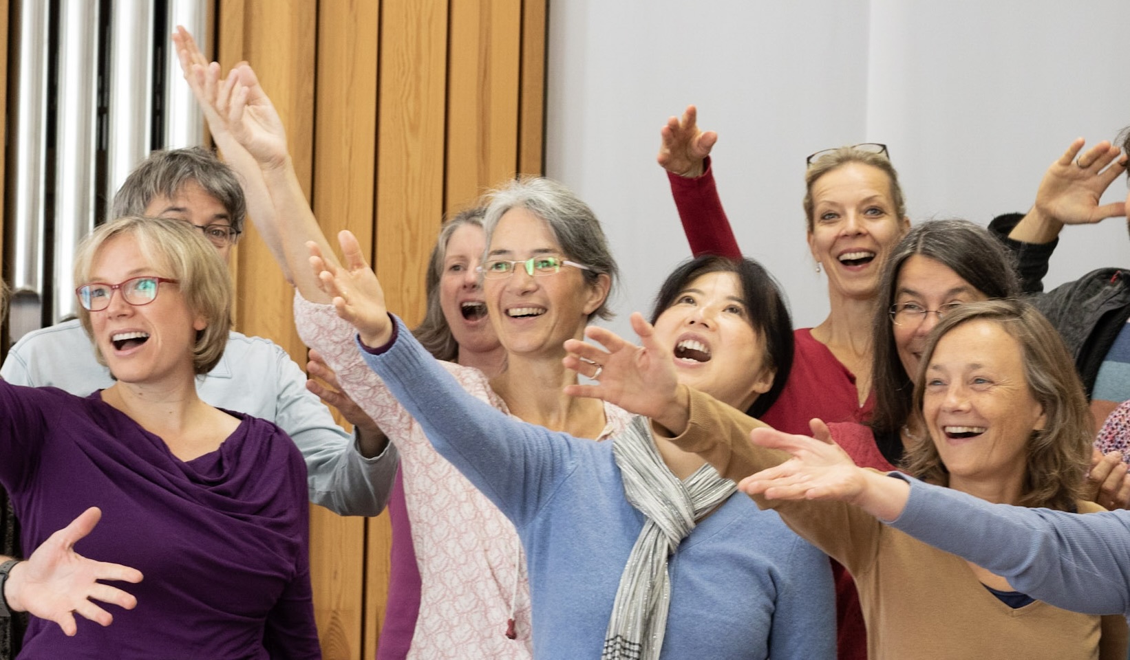 Frauen in der Stimmarbeit mit Ragna, lachend und mit ausgebreiteten Armen